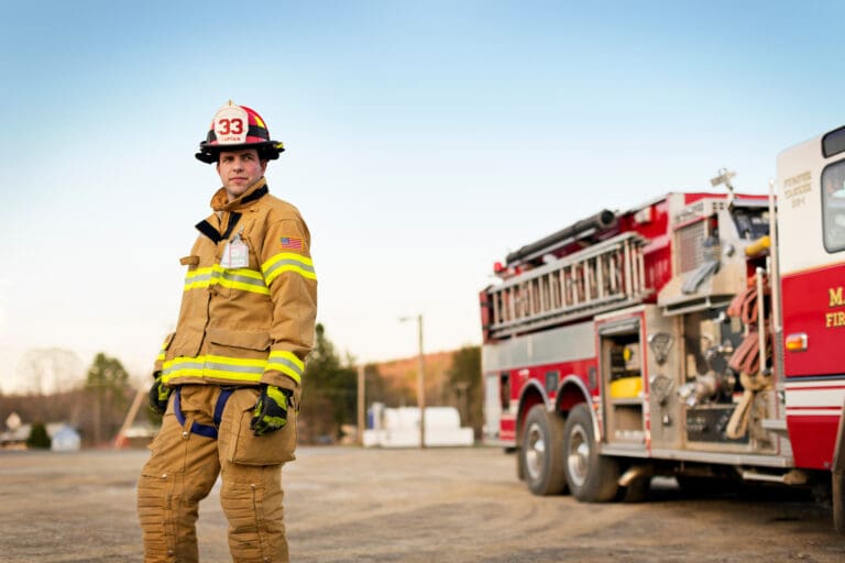 Fireman in full gear standing next to fire truck
